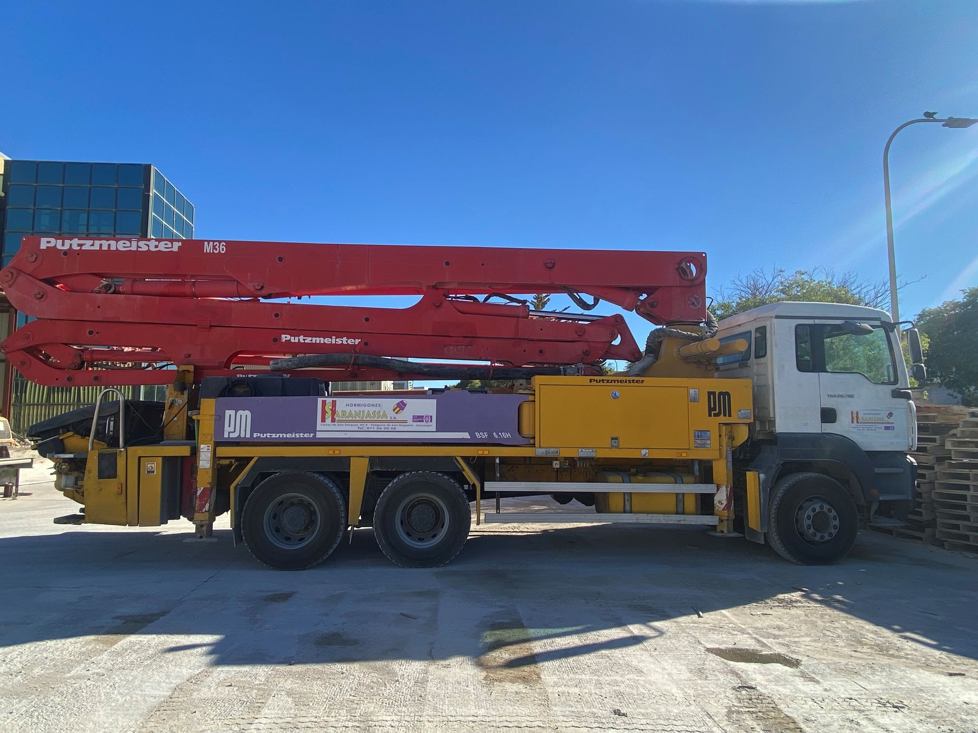 Un camión bomba de hormigón amarillo y rojo está estacionado en un estacionamiento.