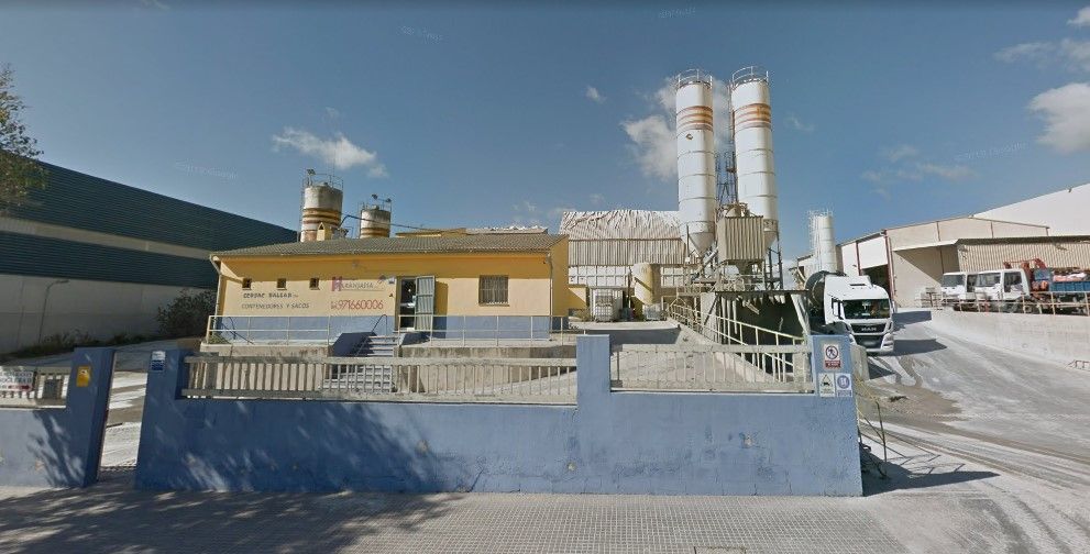 Un edificio amarillo y azul con dos silos delante.