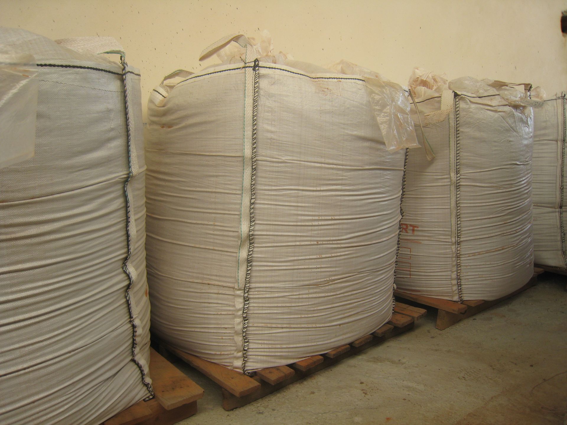 Una fila de bolsas blancas sobre palés de madera.