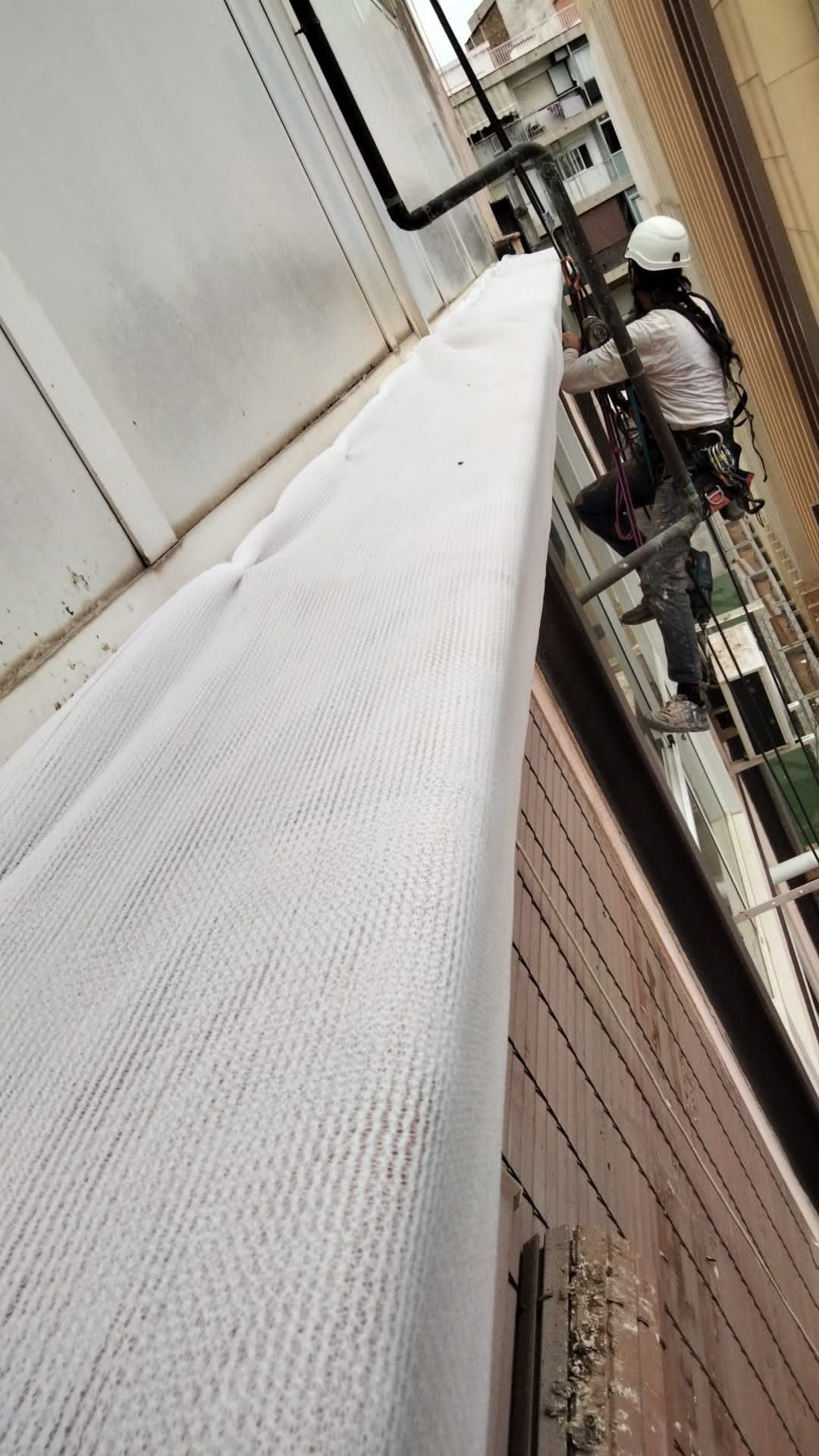 Un hombre está de pie sobre un andamio al costado de un edificio.