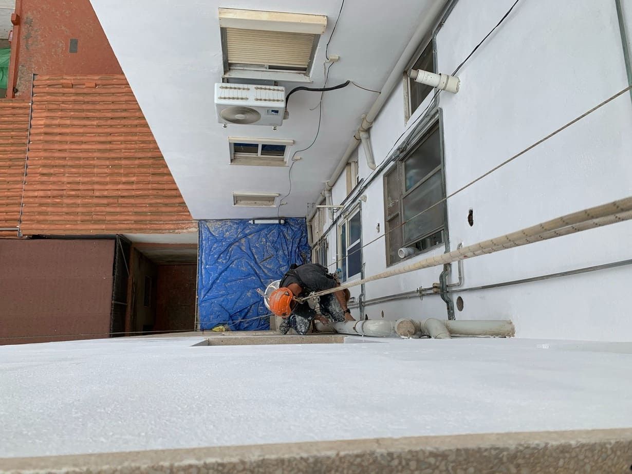 Un hombre está trabajando en el costado de un edificio.