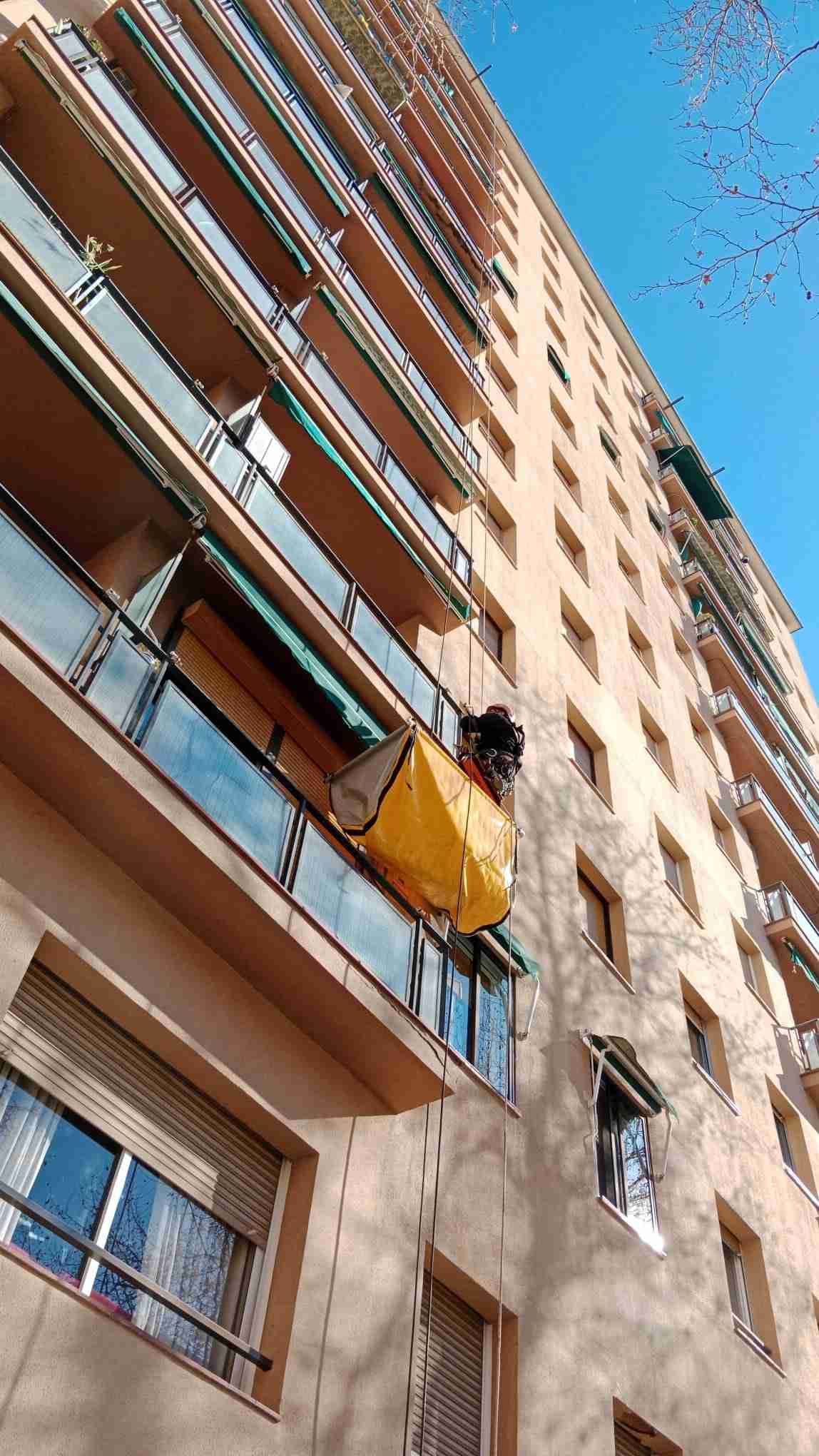 Una bolsa amarilla cuelga del costado de un edificio.