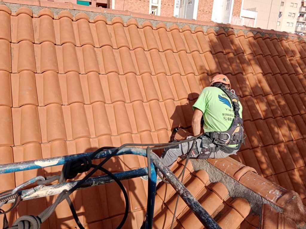 Un hombre está sentado encima de un tejado de tejas.