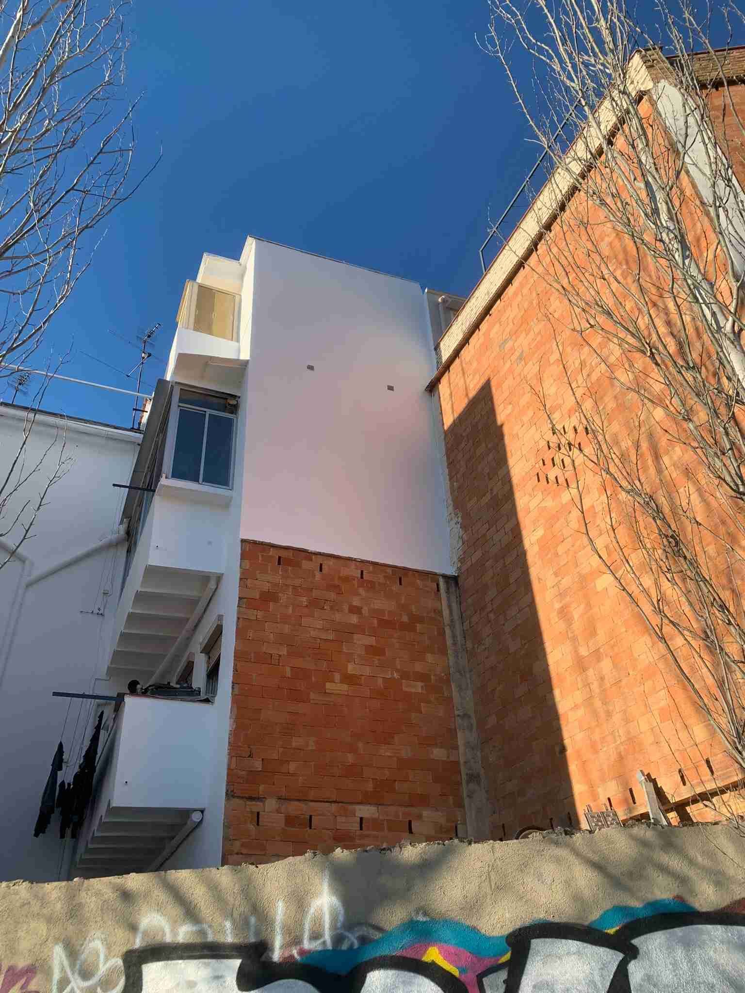 Un edificio blanco al lado de un edificio de ladrillo con graffitis en el costado.