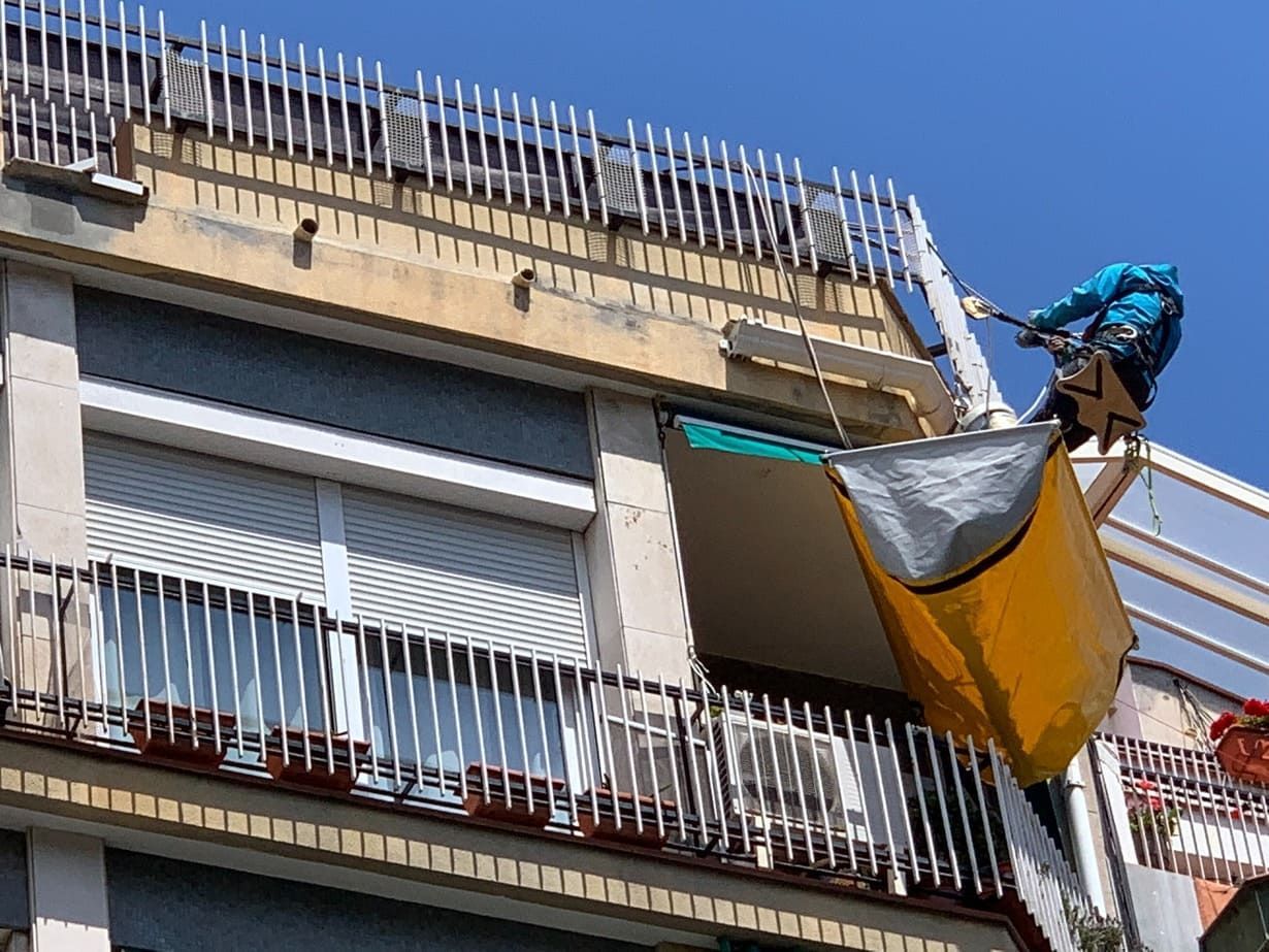 Un hombre está pintando el techo de un edificio con una lona amarilla.