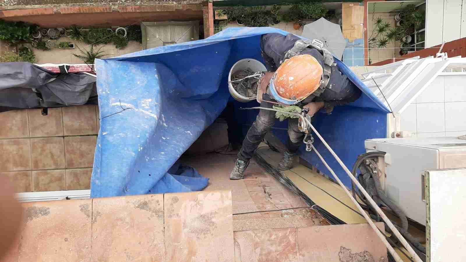 Un hombre que lleva un casco está subiendo por una lona azul.
