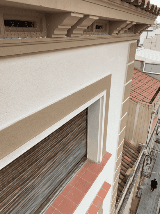 Una ventana en el costado de un edificio con una persiana.