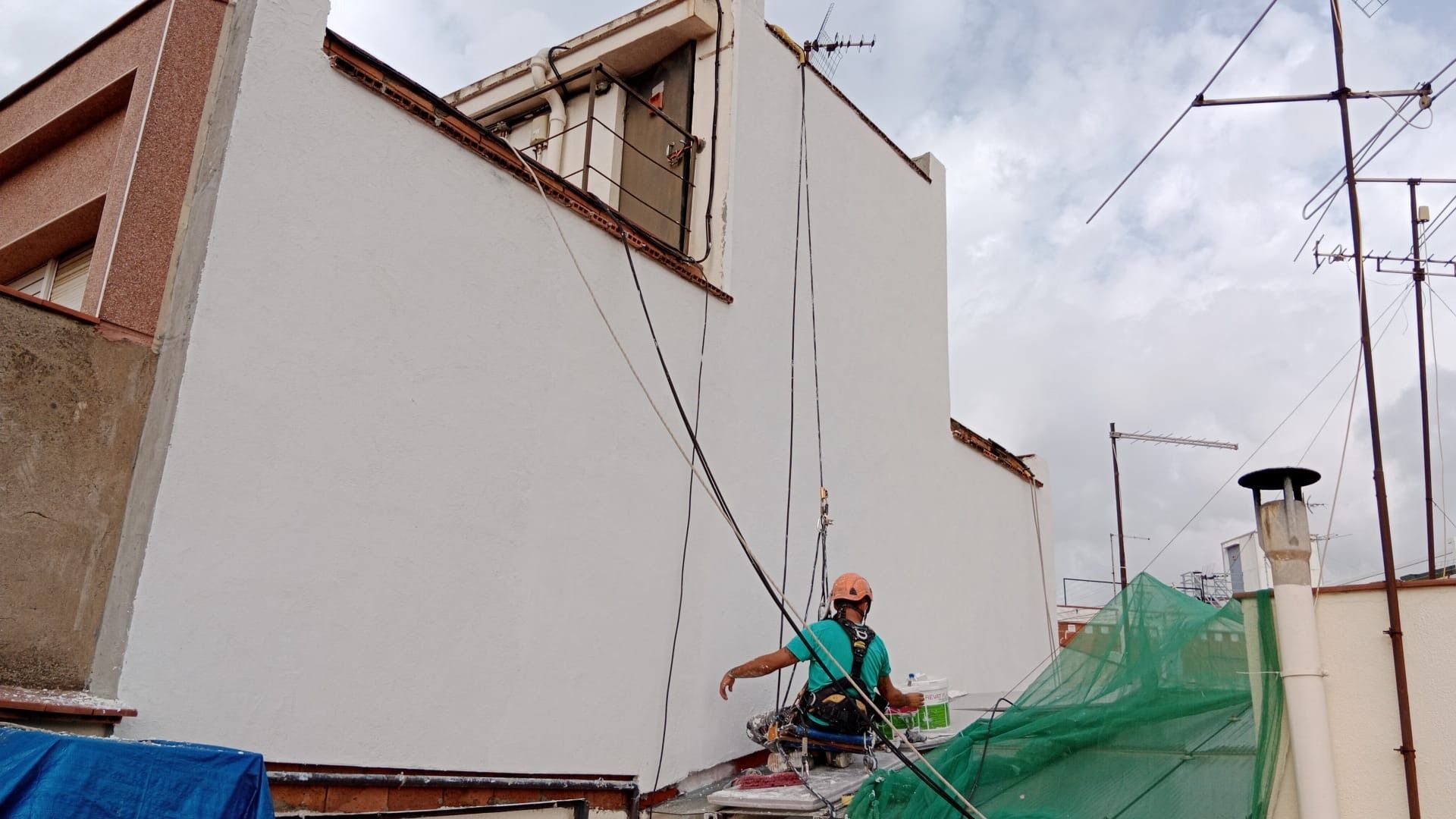 Un hombre está de pie en una escalera al costado de un edificio.