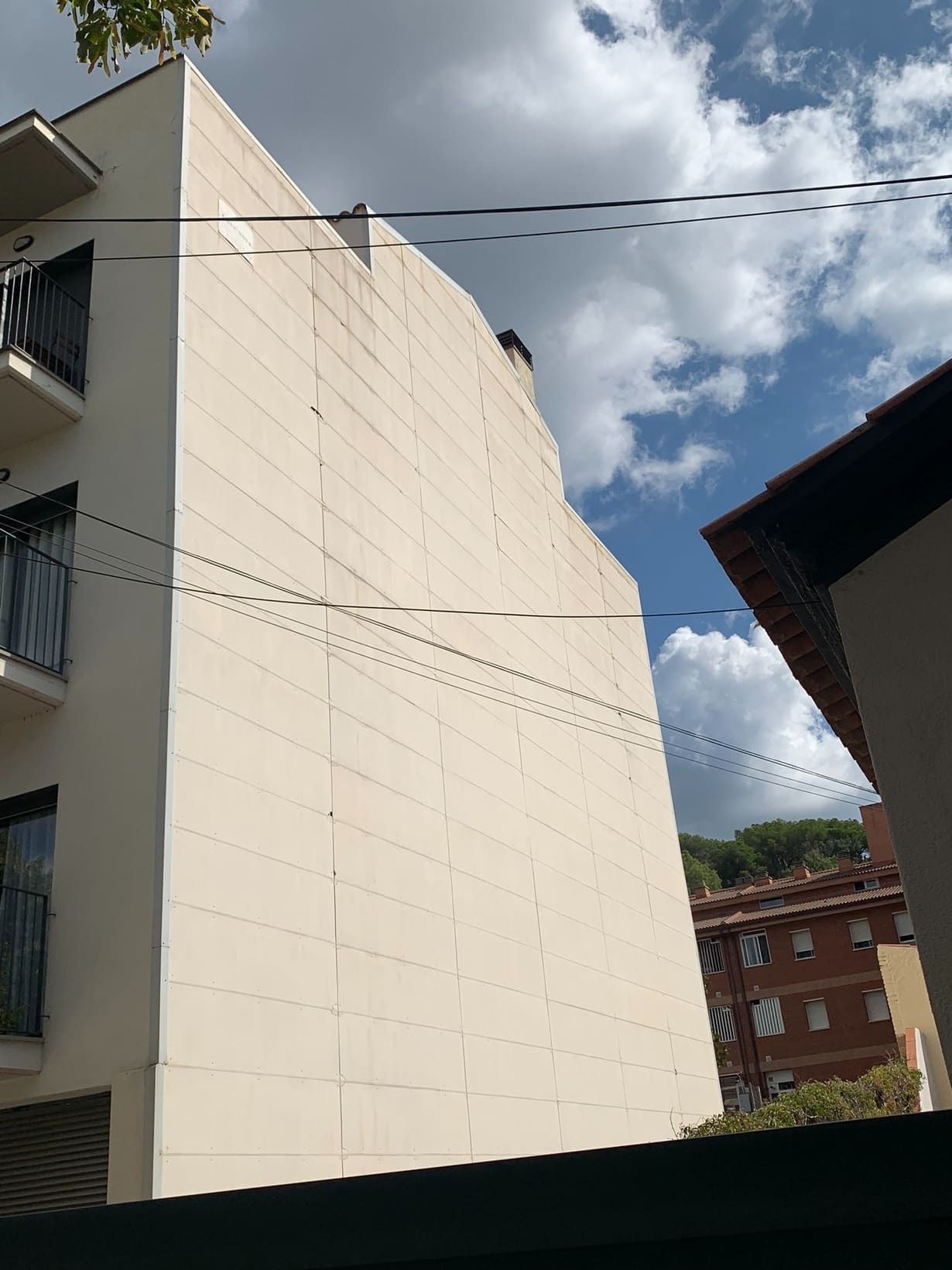 Un edificio blanco con balcones y un cielo azul al fondo.