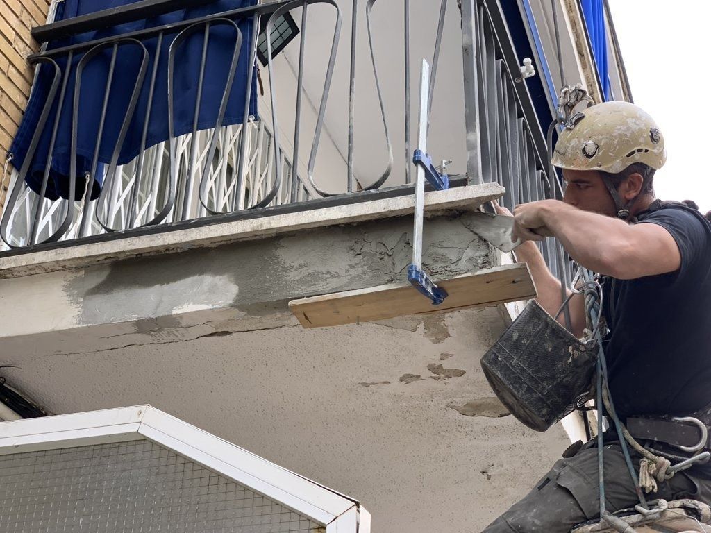 Un hombre que lleva un casco está trabajando en un balcón.