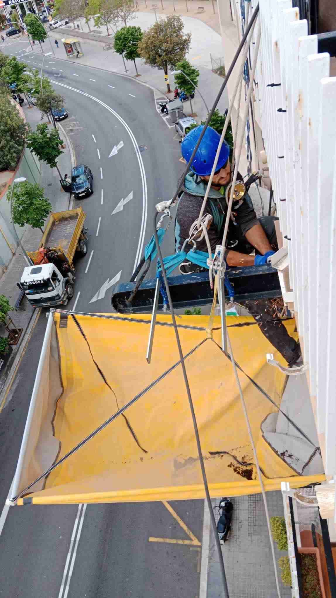 Un hombre está subiendo a un edificio con una lona amarilla.