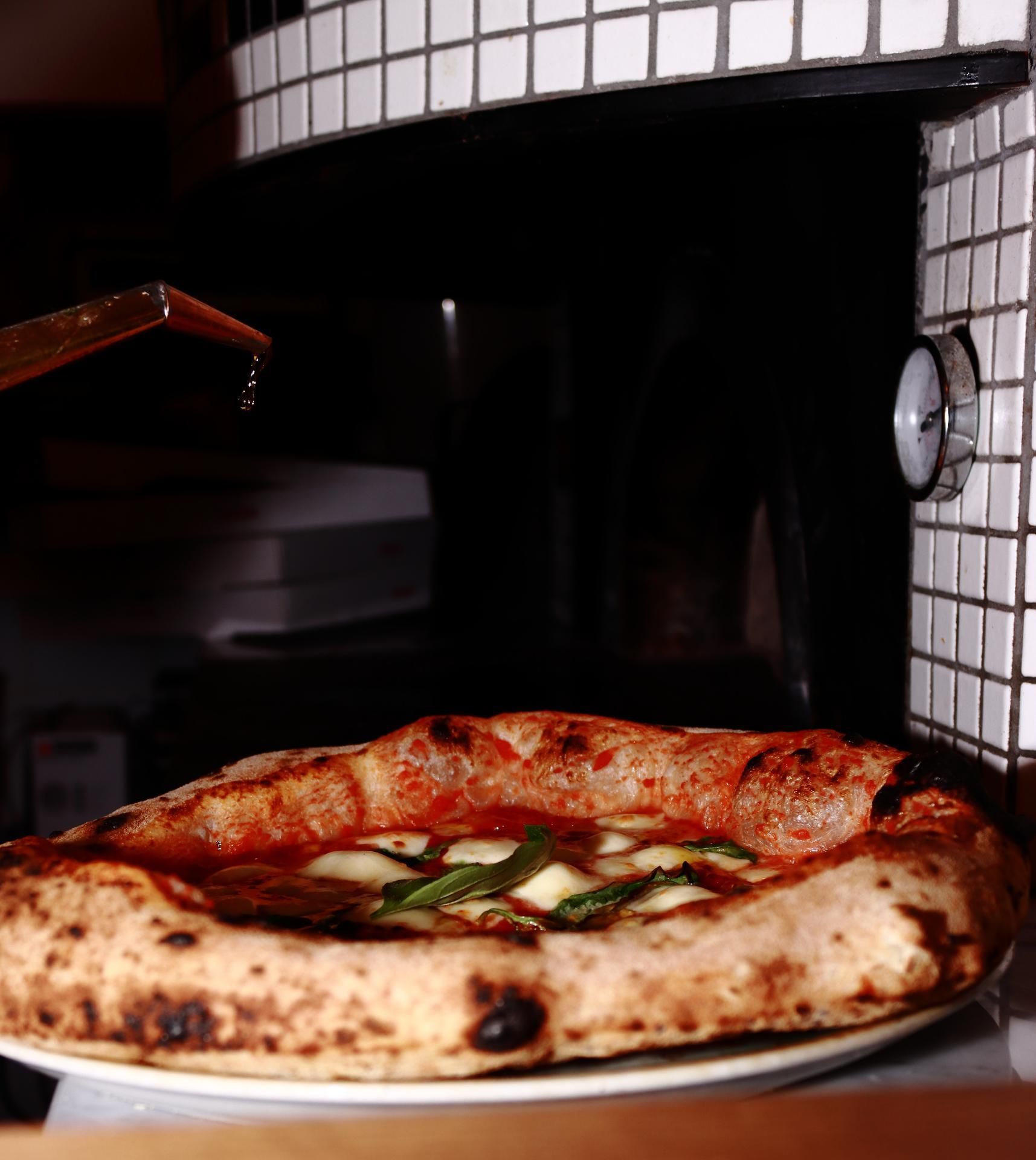 Pizza arrosée d'huile, tout juste sortie du four à bois.