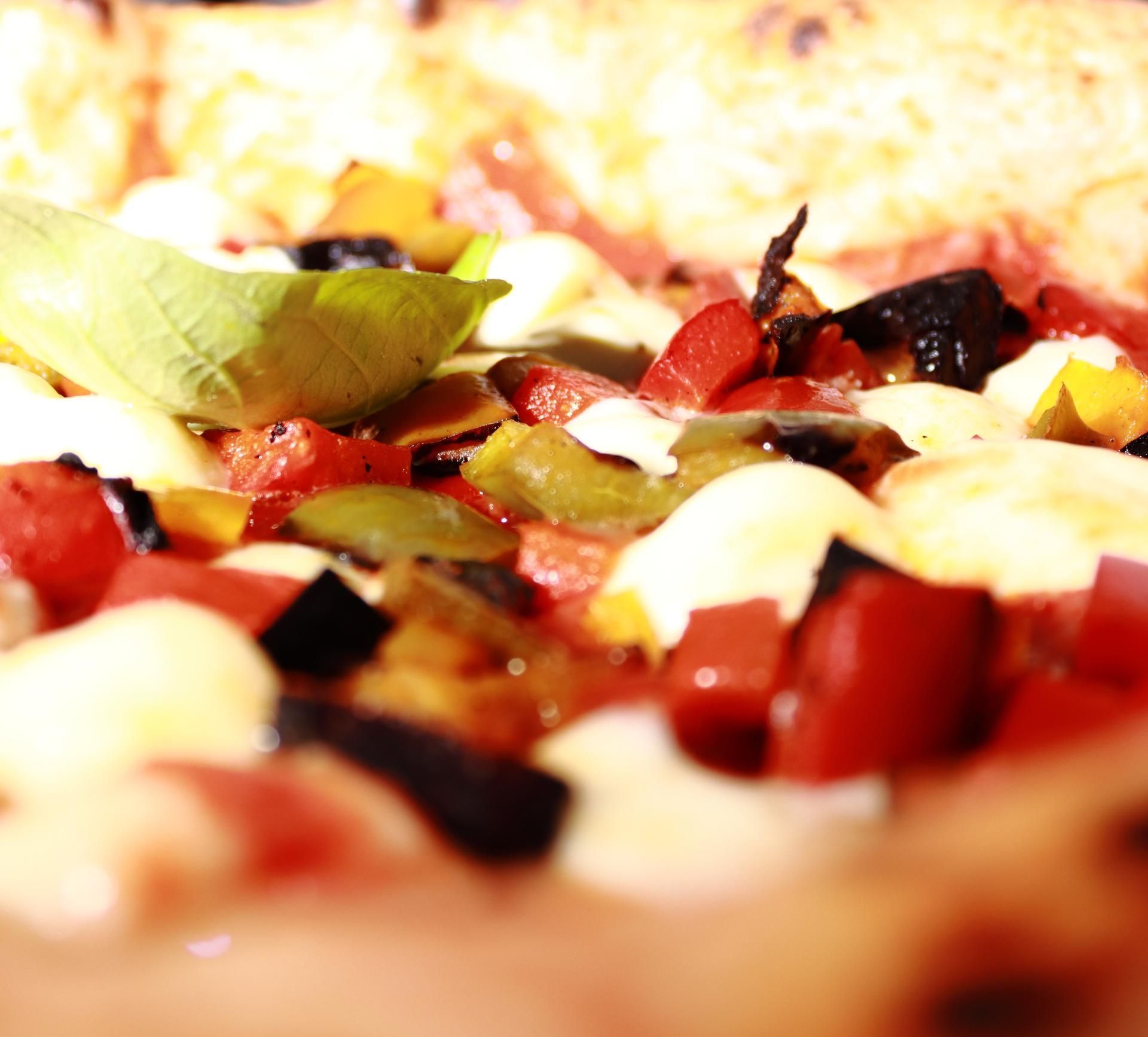 Gros plan sur une pizza garnie de poivrons rouge et vert, d'olives noires et de mozzarella.