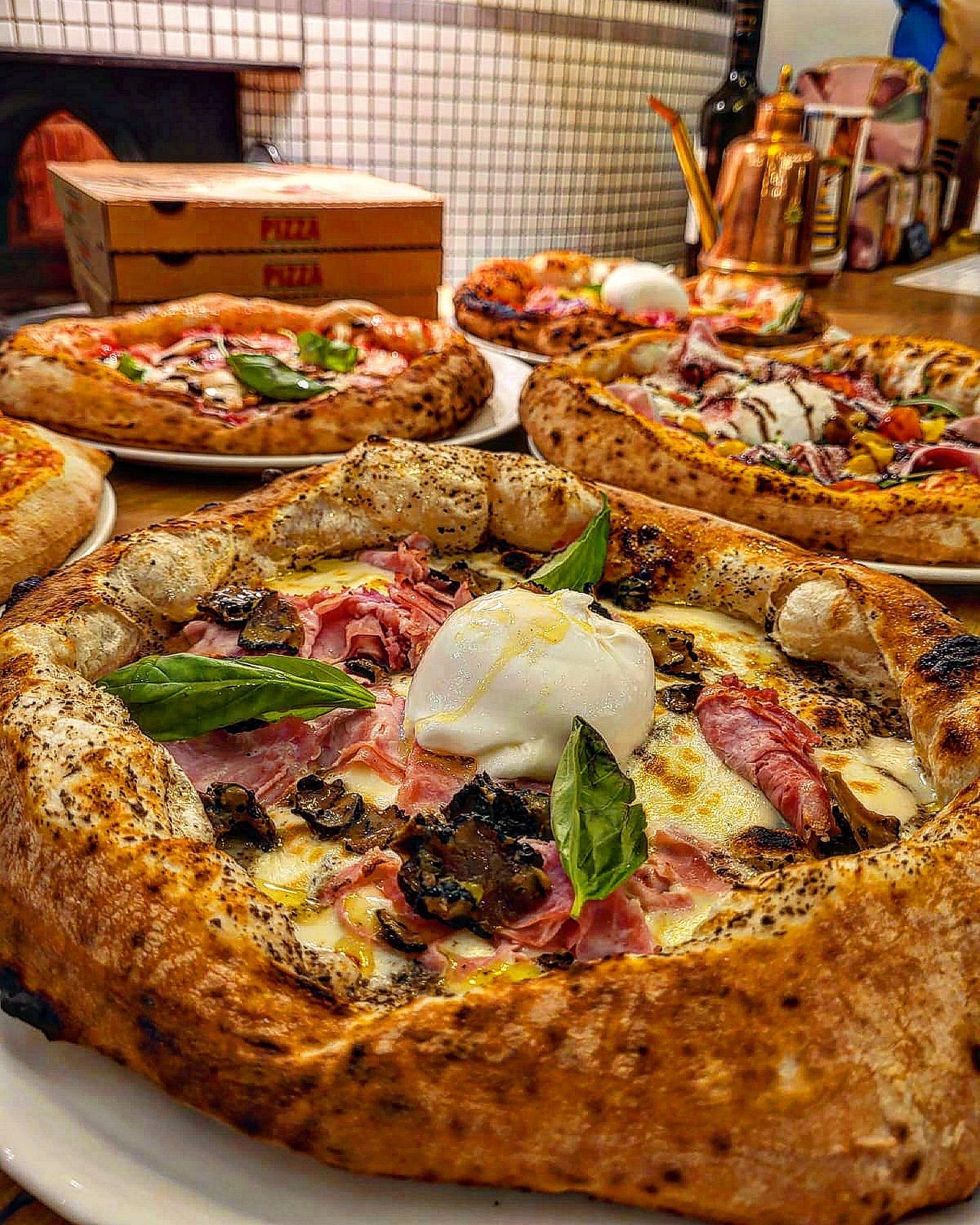 Plusieurs pizzas sur des assiettes, avec des garnitures variées ; gros plan d'une pizza avec une garniture blanche crémeuse et du basilic.