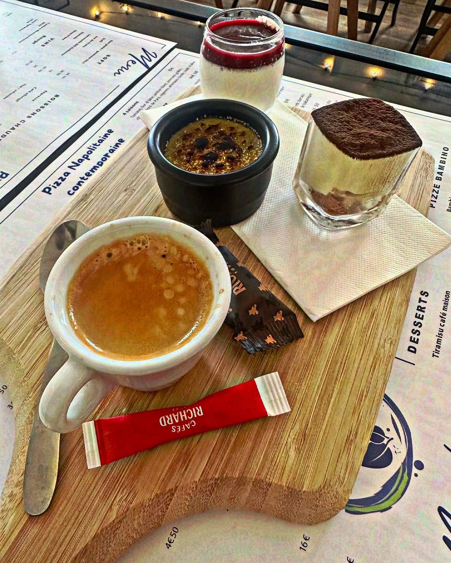 Planche en bois avec espresso, desserts : panna cotta, tiramisu, crème brûlée. Sachet de sucre rouge.