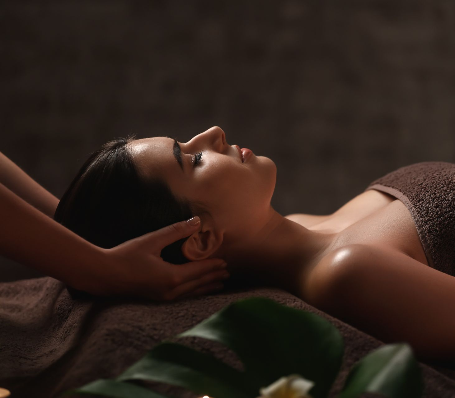 Une personne recevant un massage crânien relaxant dans un spa à l'éclairage tamisé.