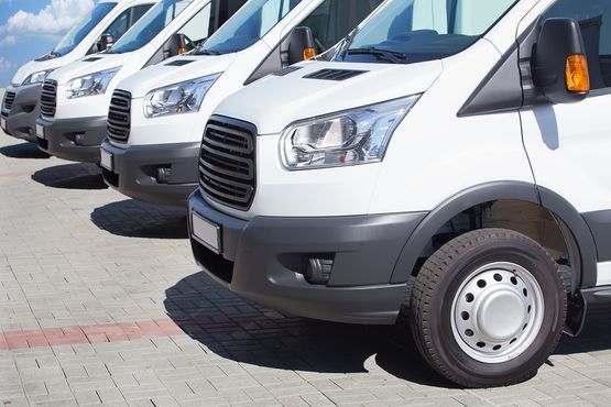 Una fila de furgonetas blancas están estacionadas en un estacionamiento.