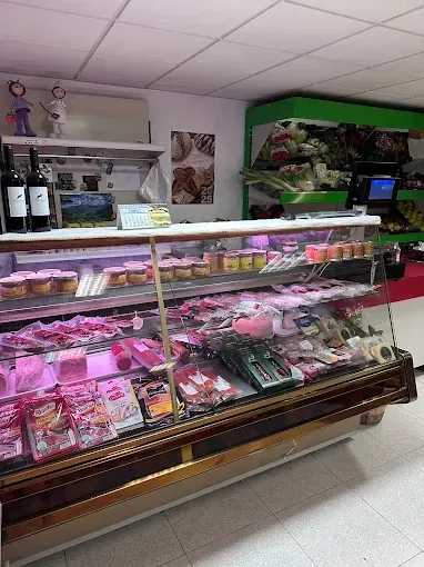 Mostrador de charcutería con carnes y alimentos preparados. Vitrina en un entorno de mercado.