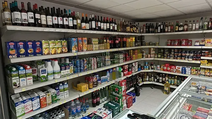 Estantes llenos de vino, bebidas y comestibles en una tienda de conveniencia.