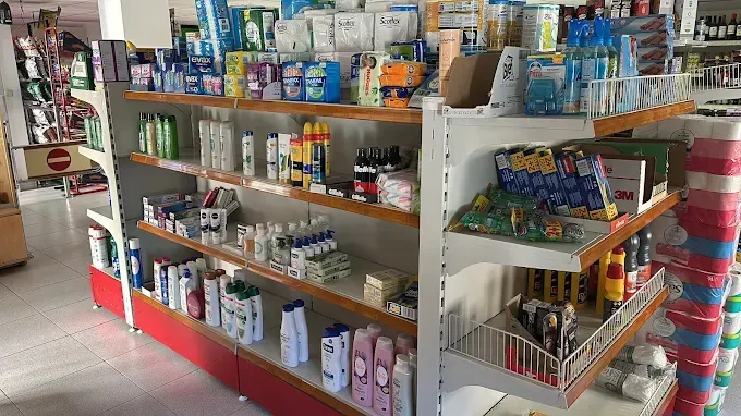 Estanterías repletas de diversos productos en una tienda; estanterías de color rojo y blanco.