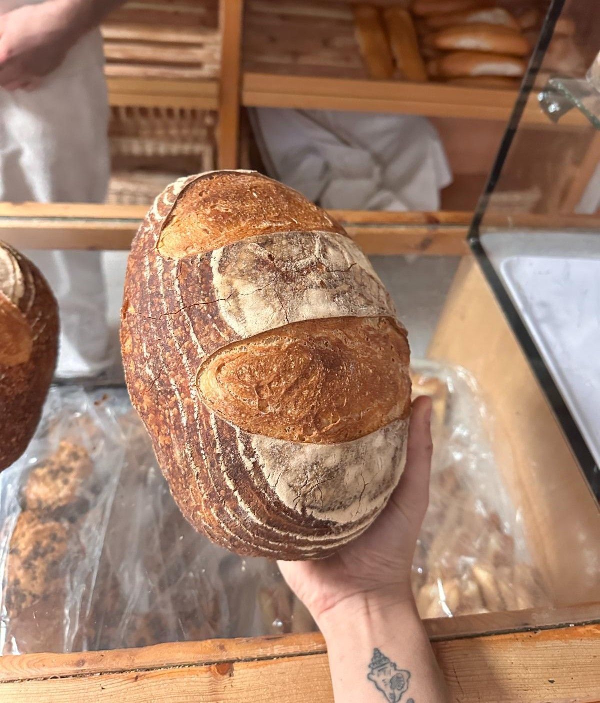 Primer plano de una hogaza de pan crujiente y dorado. Se aprecian algunos granos en la esquina inferior izquierda.