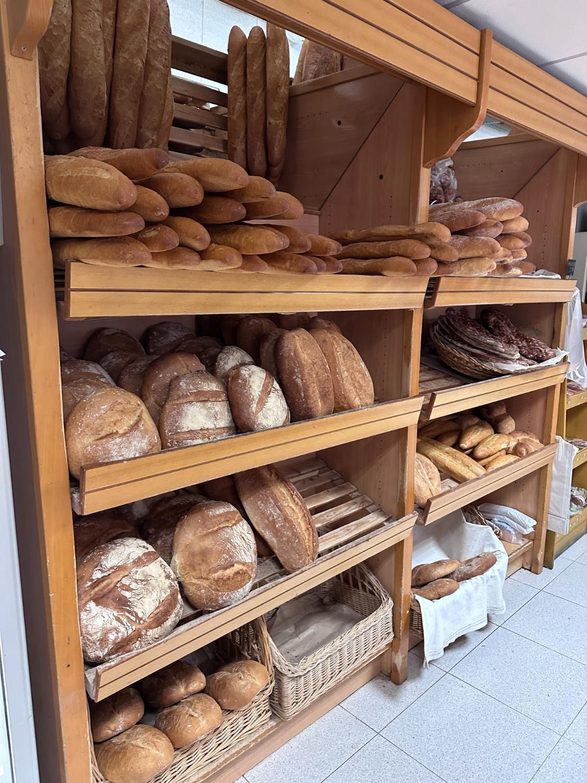 Montón de hogazas de pan crujientes y doradas, espolvoreadas con harina, en una cesta.