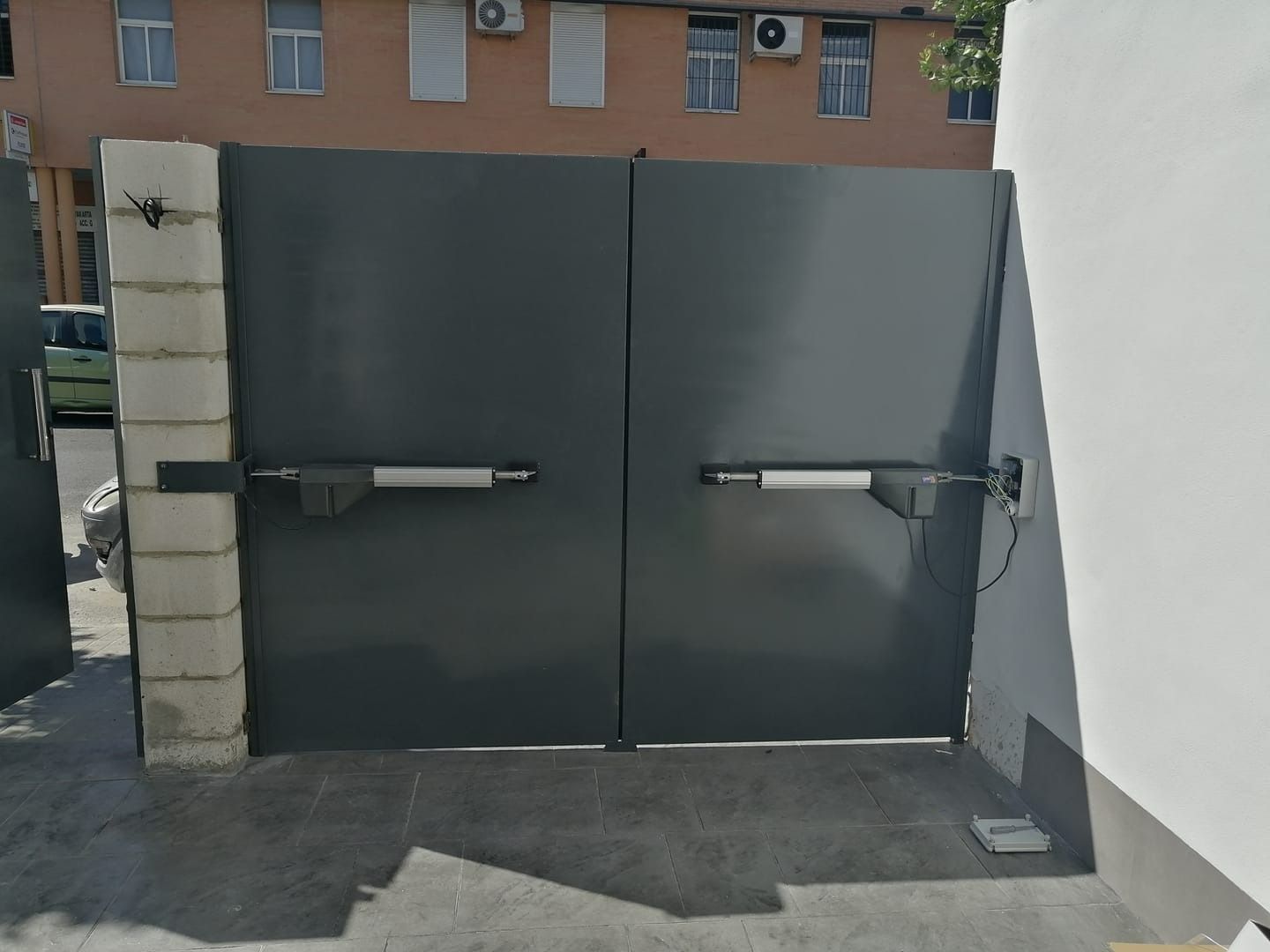 Una puerta negra con una pared de ladrillos detrás.