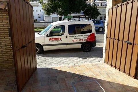 Una furgoneta blanca está aparcada delante de una puerta de madera.