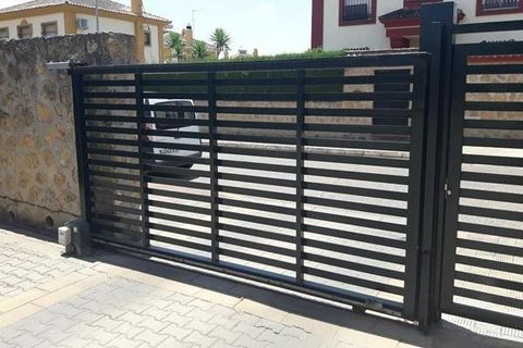 Una puerta corrediza se abre a un camino de entrada con un automóvil estacionado detrás de ella.