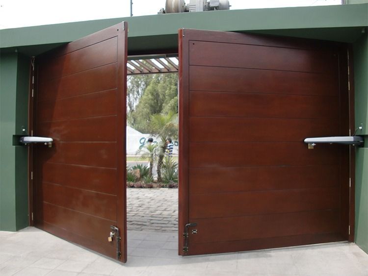 Un par de puertas de garaje de madera se abren a un camino de entrada.