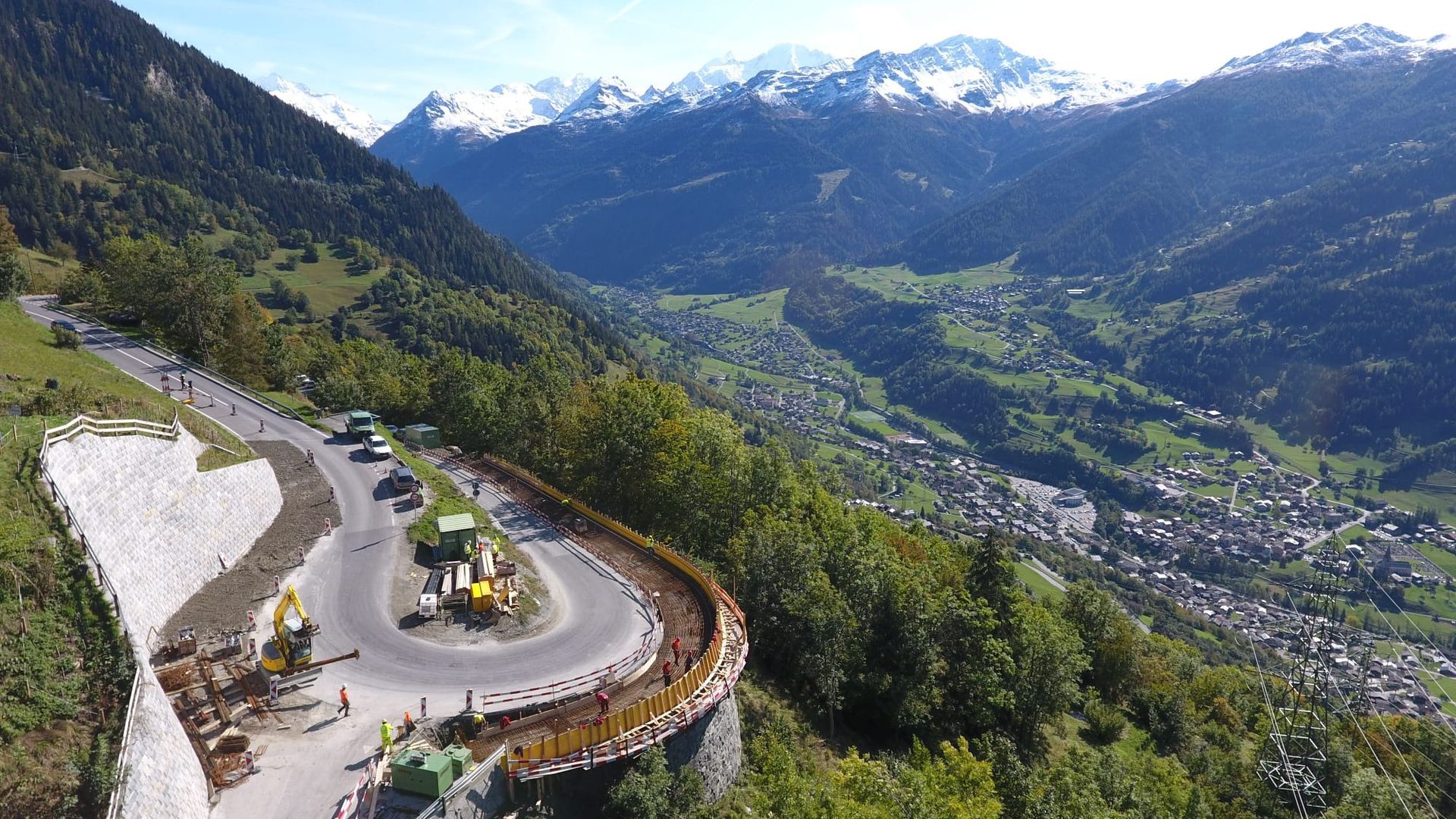 Une vue aérienne d'une route traversant une vallée avec des montagnes en arrière-plan.