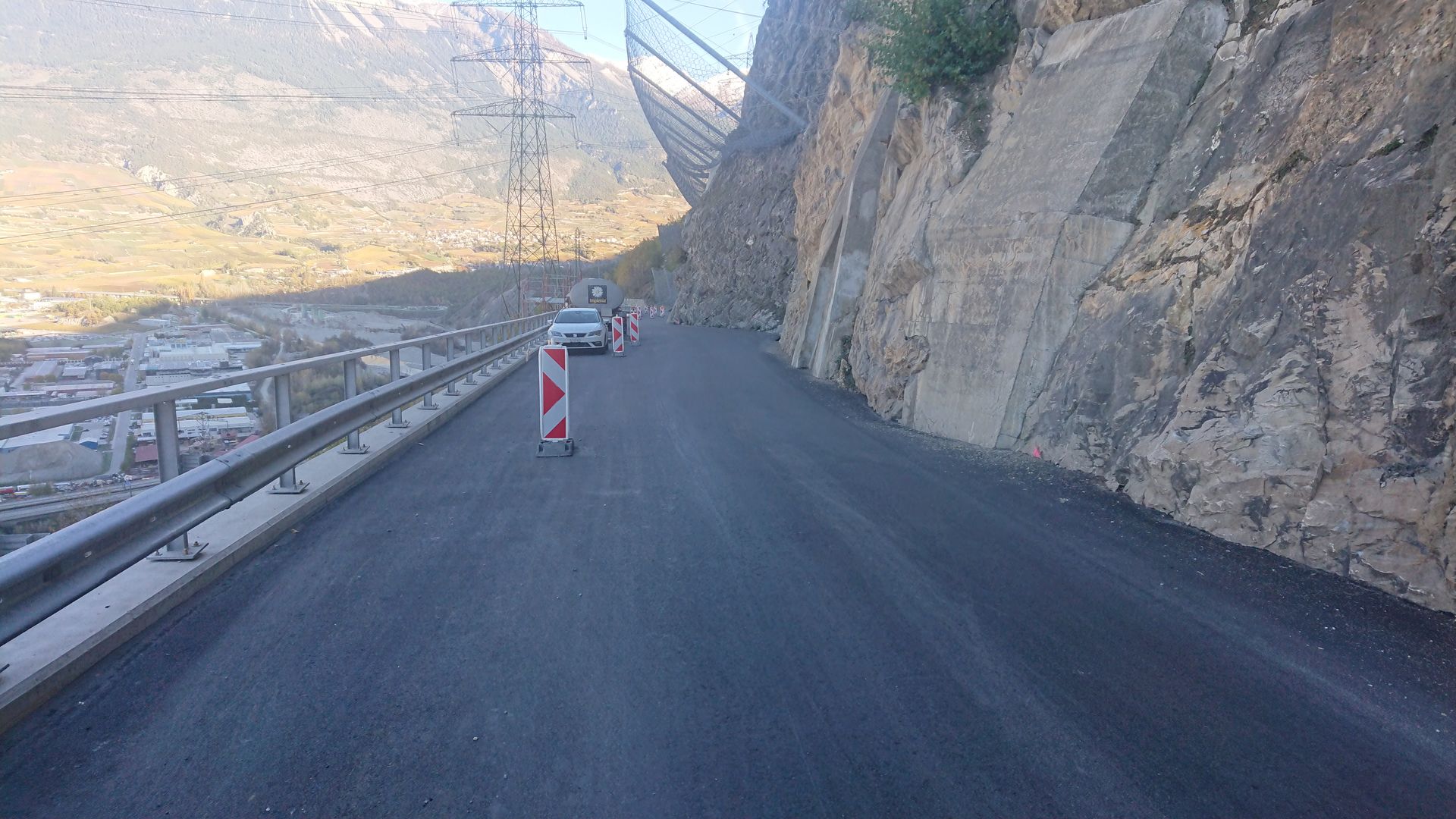 Une voiture roule sur une route à côté d'une montagne.