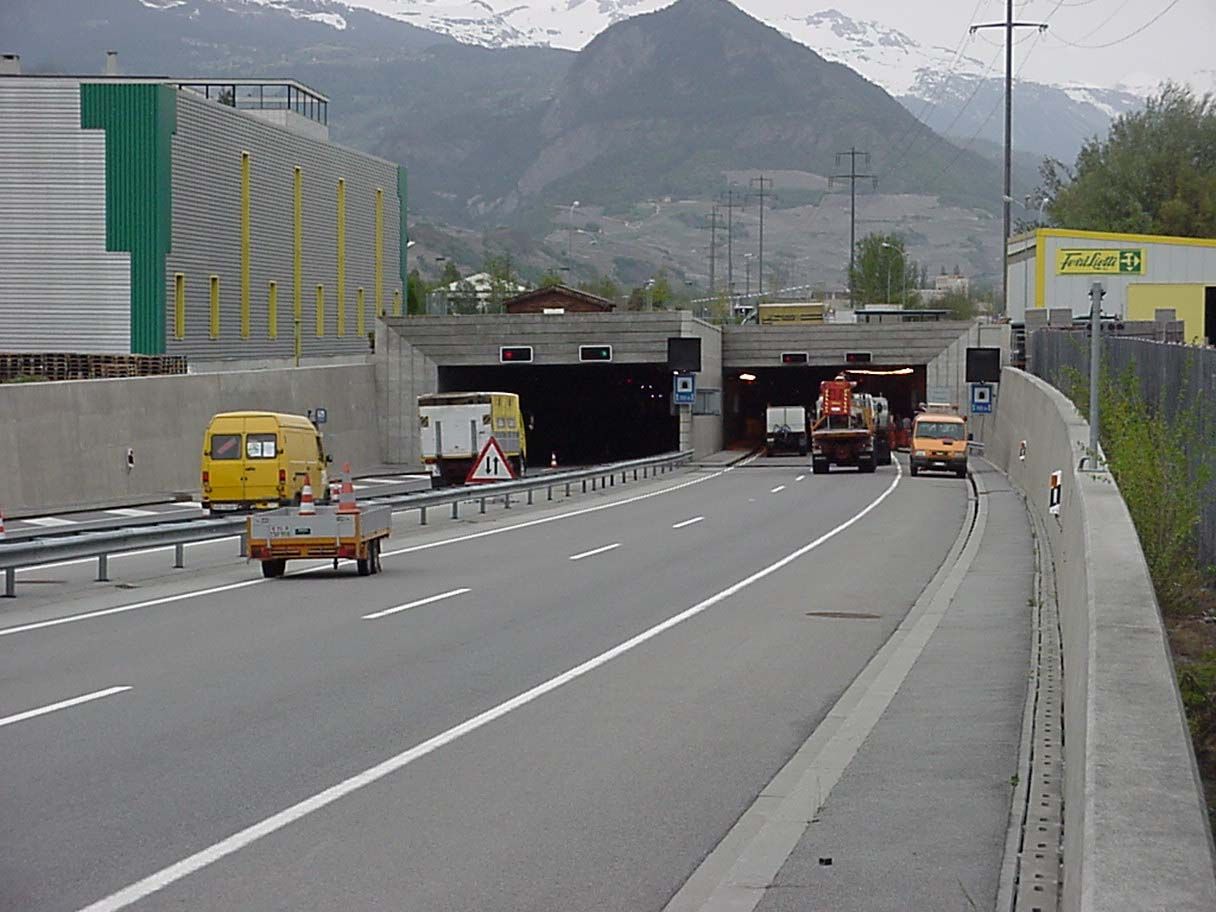 Une camionnette jaune roule sur une autoroute à côté d'un tunnel