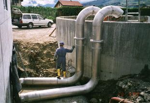 Un homme se tient debout à côté d'un tuyau en acier inoxydable.