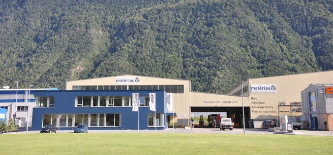 Un grand bâtiment bleu et beige avec une montagne en arrière-plan.
