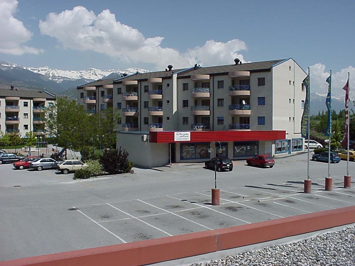 Un parking devant un immeuble avec un auvent rouge