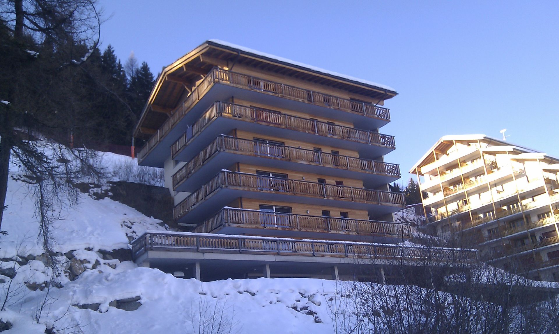 Un grand bâtiment avec beaucoup de balcons est entouré de neige