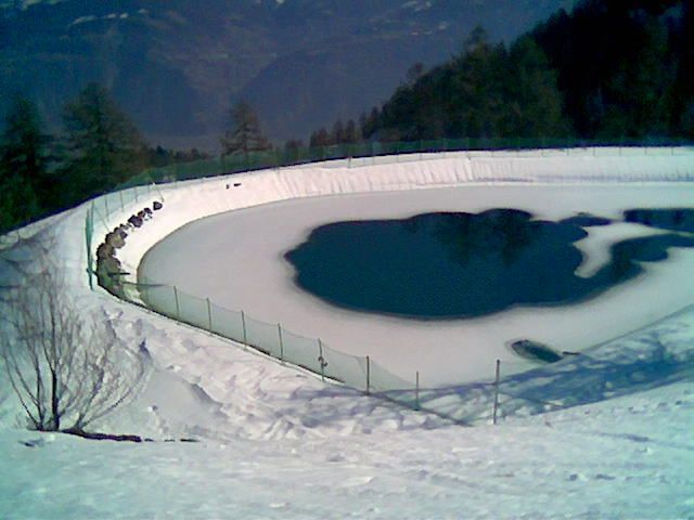 Un étang recouvert de neige avec une clôture autour
