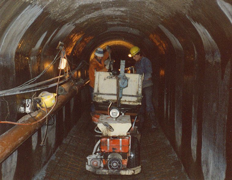 Deux hommes travaillent dans un tunnel avec une machine sur laquelle est inscrit la lettre h