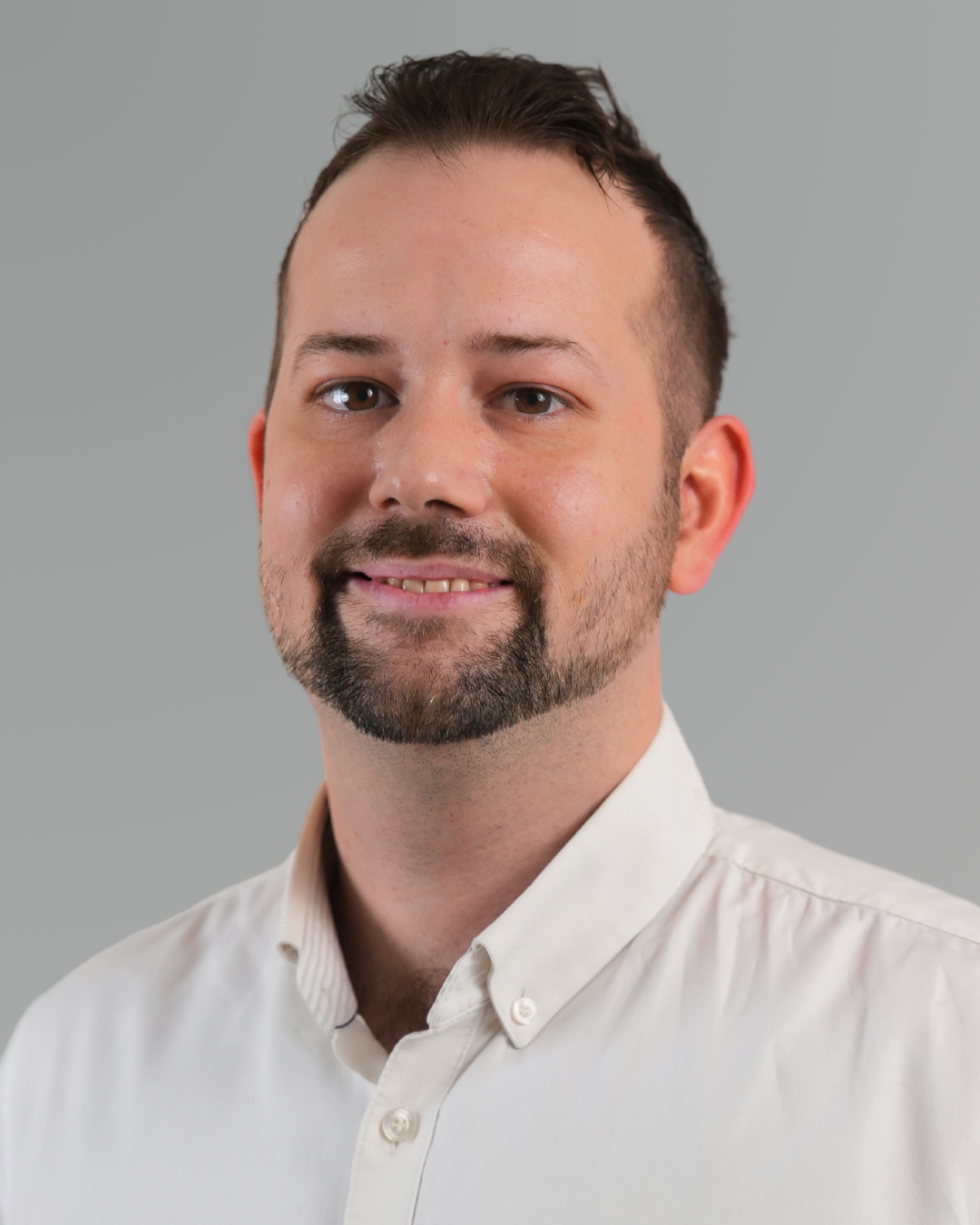 Zwei Personen in Anzügen analysieren an einem hellen Schreibtisch Daten auf einem Tablet und ausgedruckte Berichte.