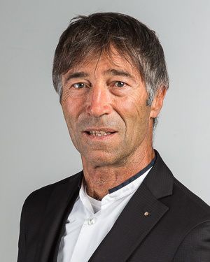 Zwei Personen in Anzügen analysieren an einem hellen Schreibtisch Daten auf einem Tablet und ausgedruckte Berichte.