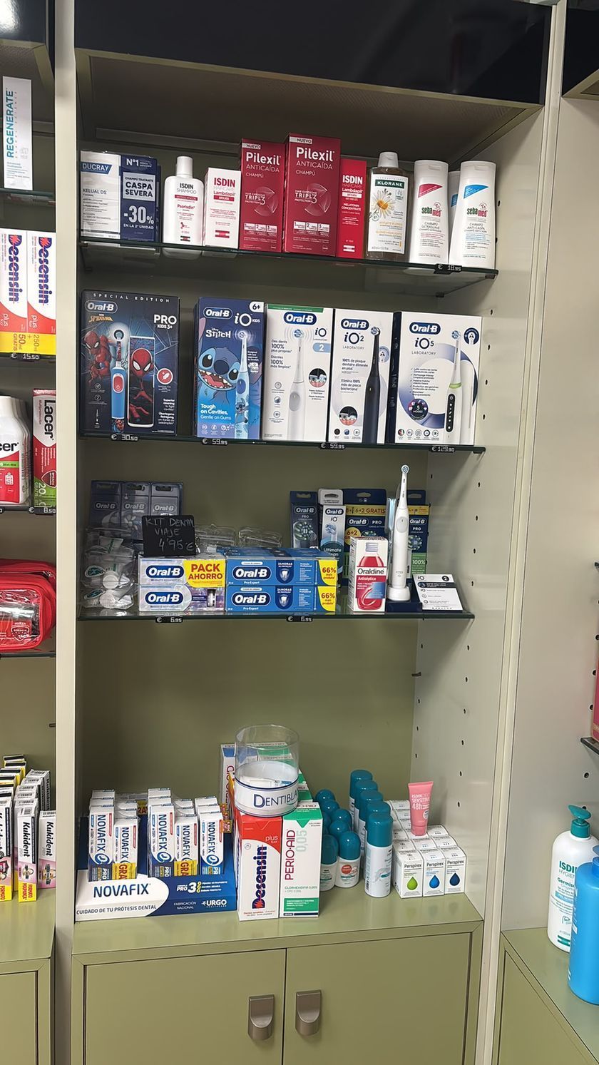 Estante de una tienda abastecida con cajas y tubos de pasta de dientes variados en el pasillo de una farmacia.