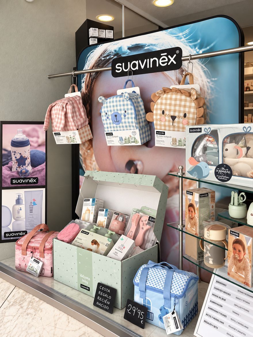 Expositor de productos para bebés Suavinex con bolsas de colores, artículos de aseo y accesorios en las estanterías