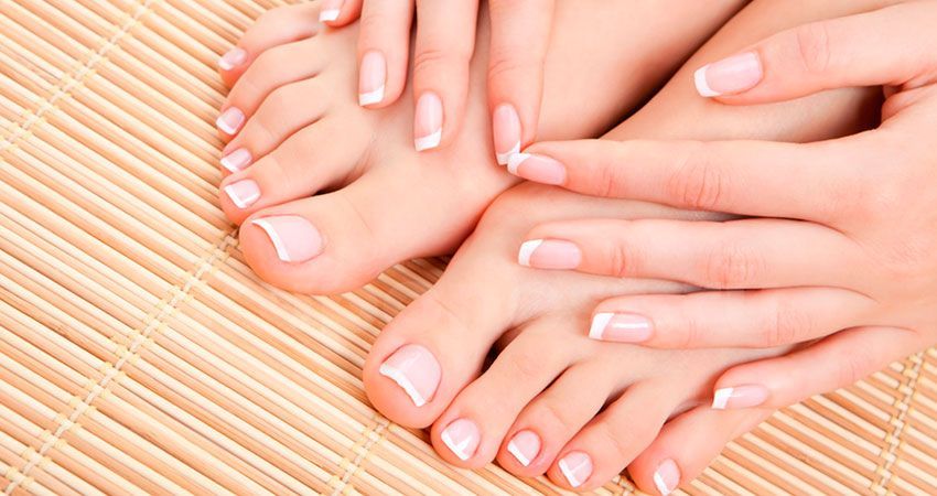 Un primer plano de los pies y las manos de una mujer sobre una estera de bambú.