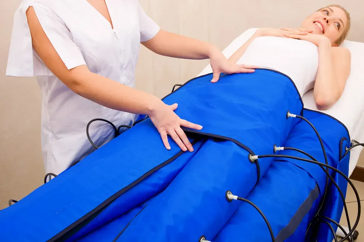 Una mujer está acostada en una cama con una manta azul sobre sus piernas.