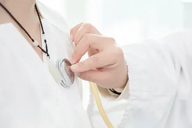 Un médico utiliza un estetoscopio para escuchar los latidos del corazón de un paciente.