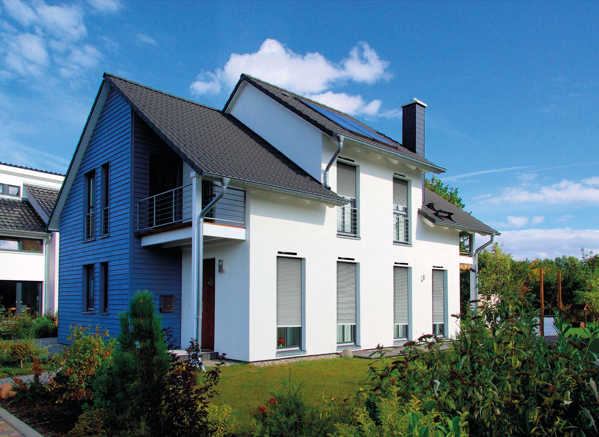 Maison avec tuile noire et façade blanche, avec volet roulant solaire de couleur blanche