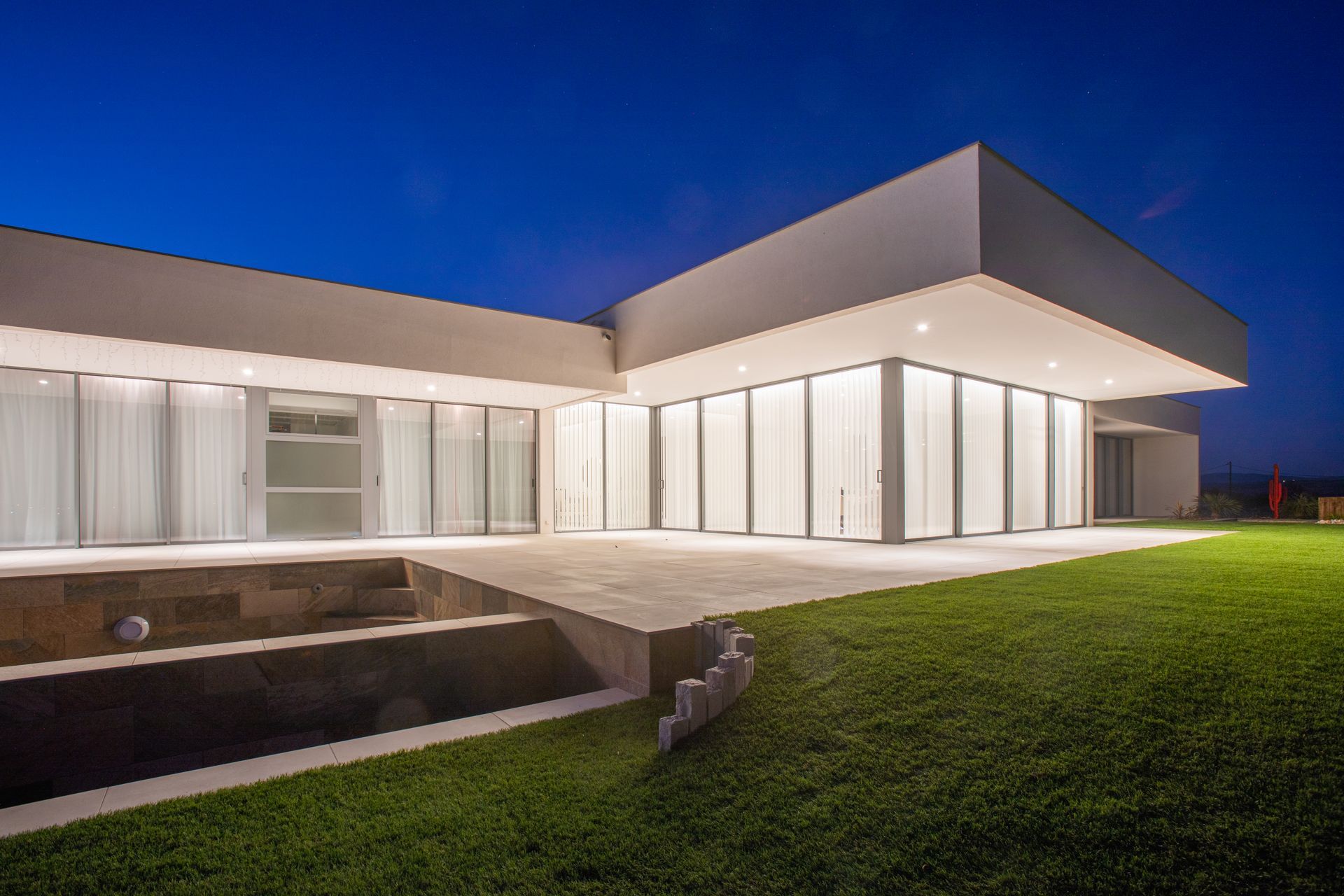 Baie vitrée sur villa moderne blanche avec éclairage la nuit