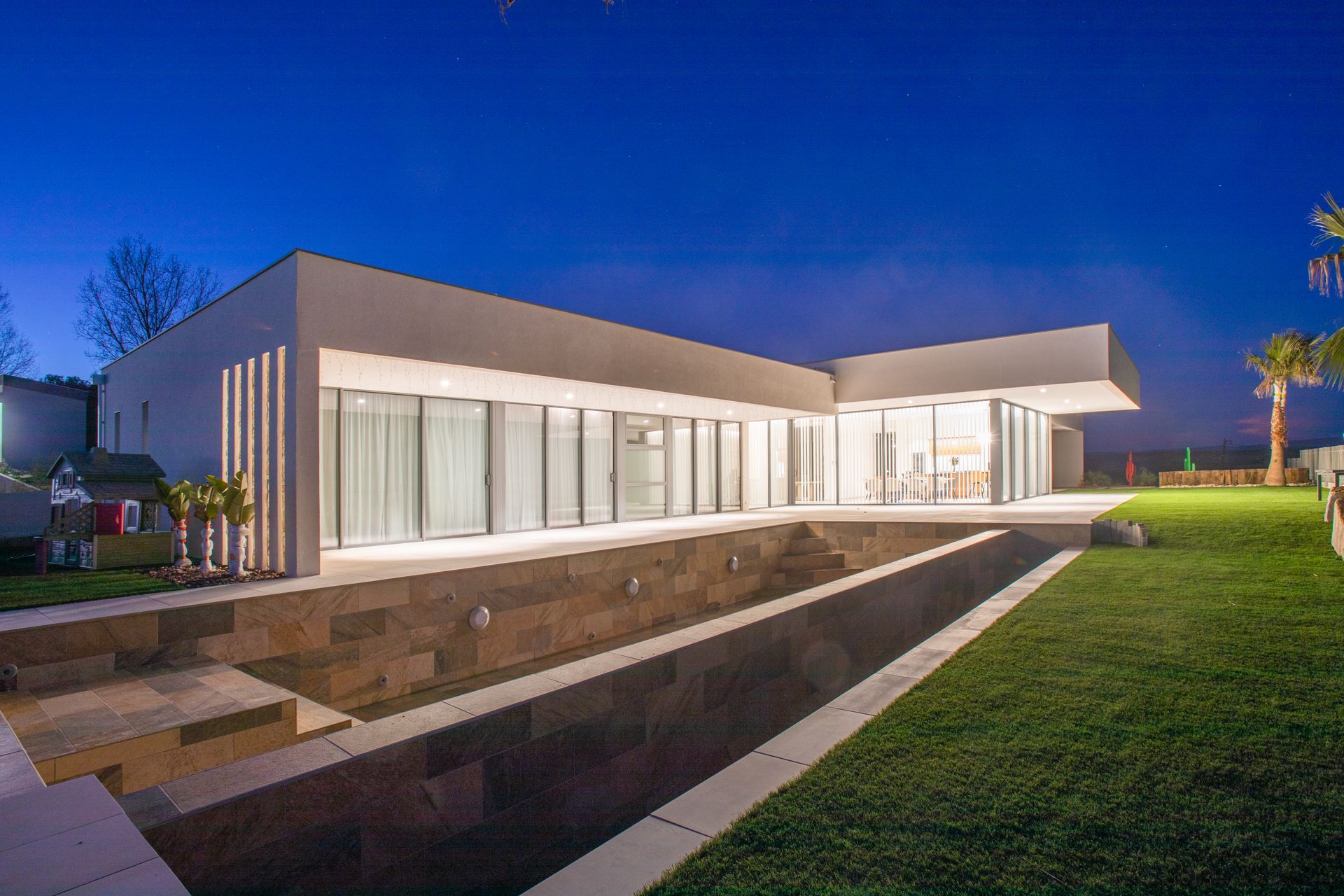 Baie vitrée sur villa moderne blanche avec éclairage la nuit vue 2