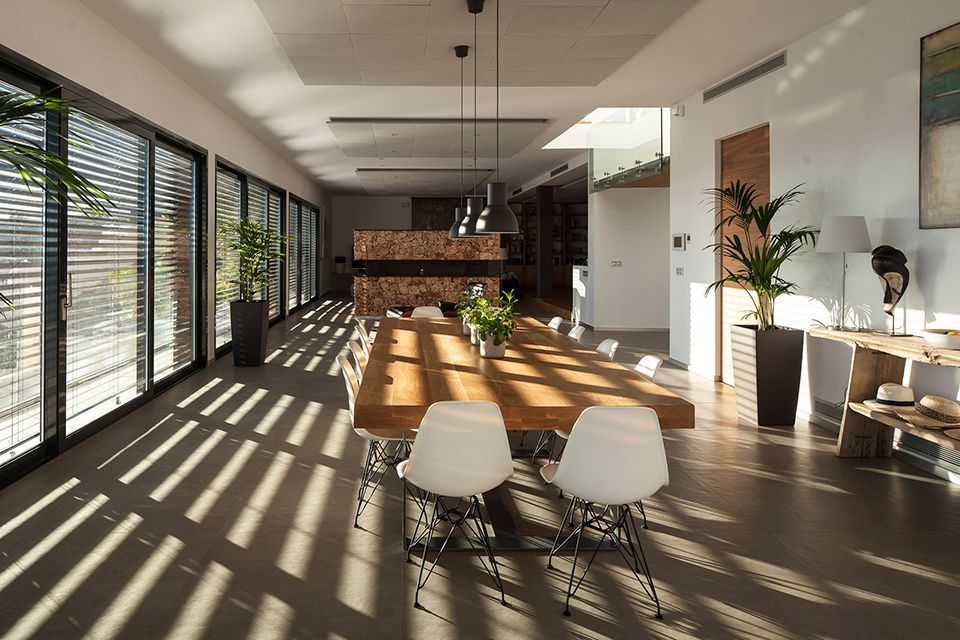 Intérieur d'une maison avec grande baie vitrée et brise-soleil aui fait un jeux d'ombre dans la piéce
